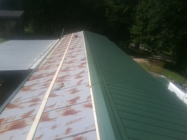 Old rusted panels beside newly installed green metal roofing — Wind Damage Roof Repair by Roofing Brothers in Fields