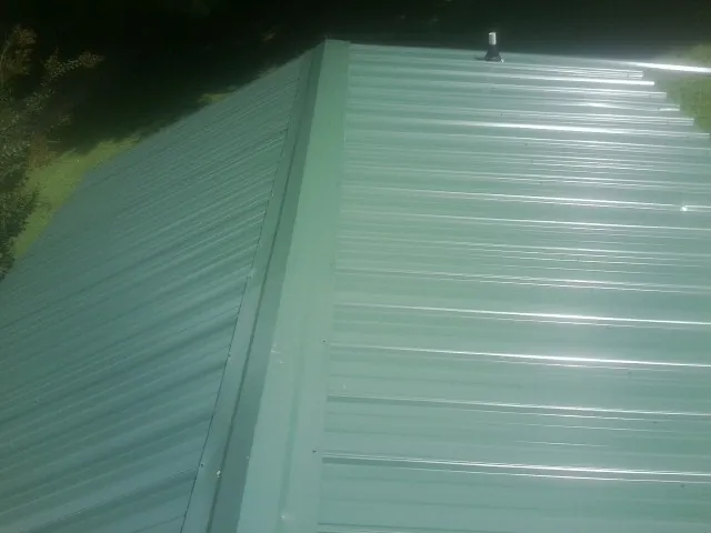 New green metal panels meeting at the ridge of a roof — Flat Roof Repair work by our crew in Fields