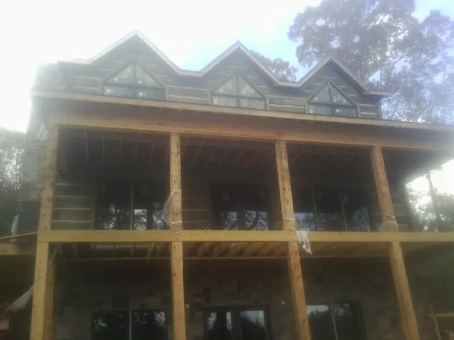 Dormers and porch framing on a large log home under construction — Roof Coating work by our crew in Fields
