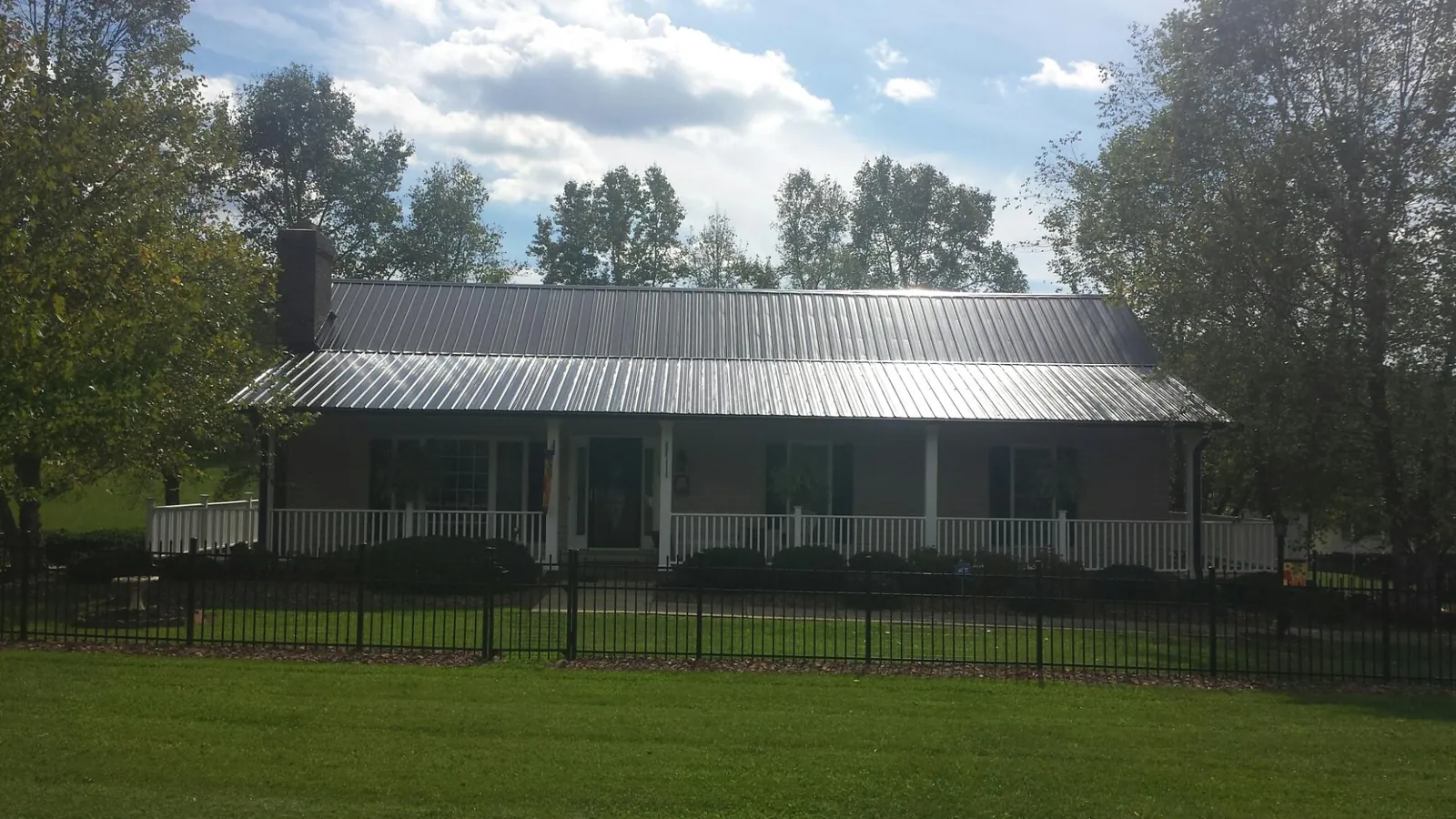 Gray metal roof on a brick ranch with a full width front porch — Gutter Guard Installation work by our crew in Fields