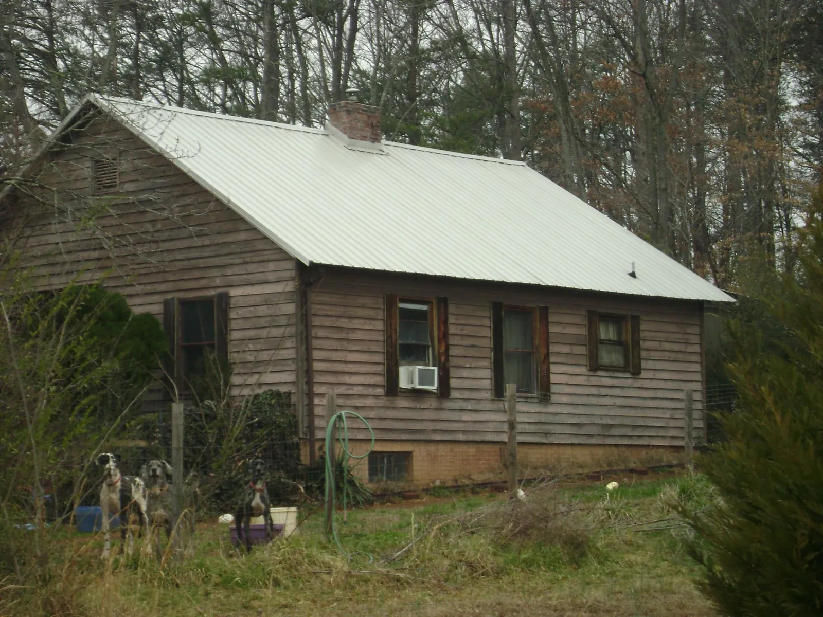 White metal roof on an old wood sided farmhouse, from a Metal Roof Installation job in Fields