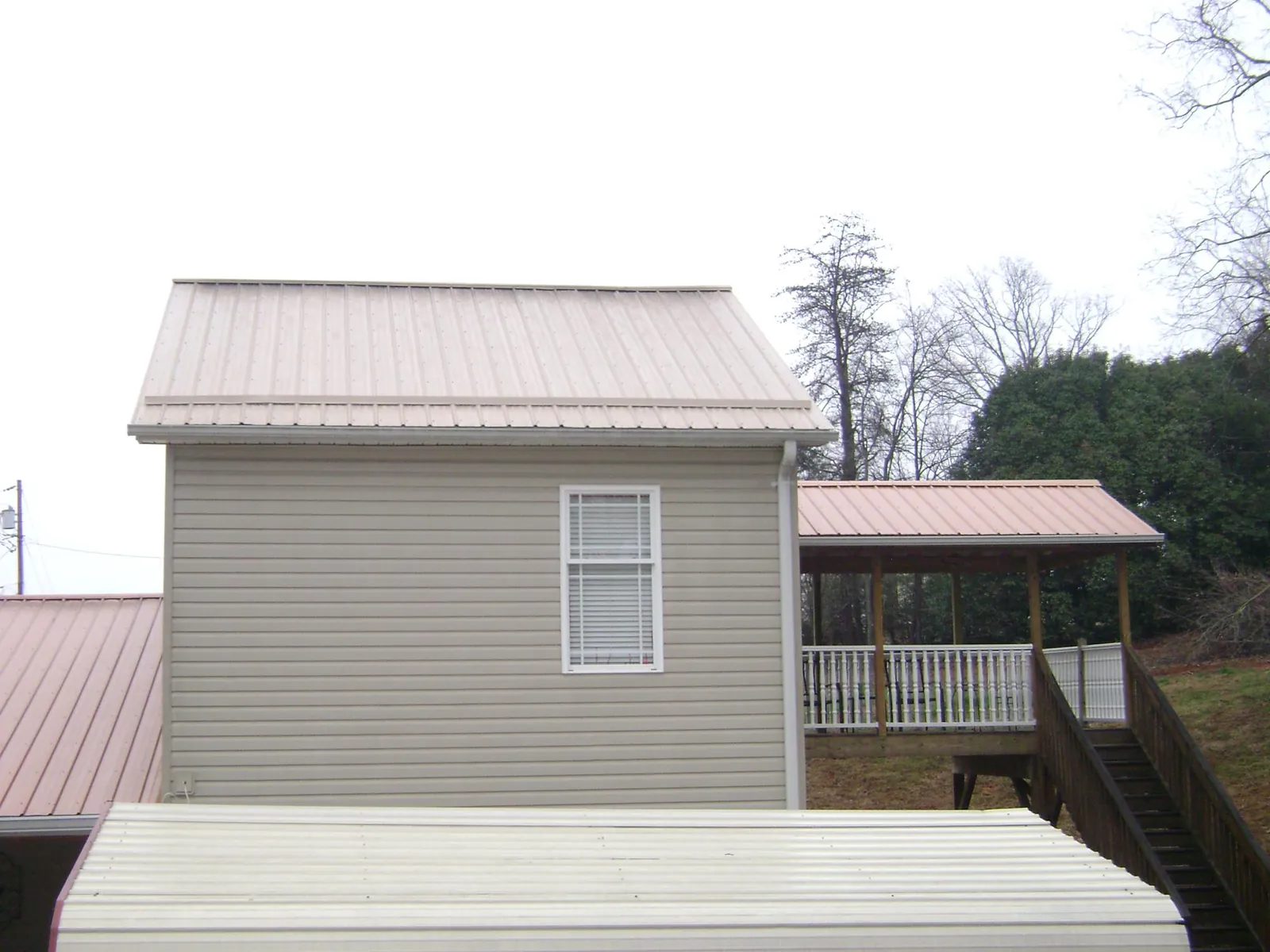 Tan metal roofs on a two story addition and attached porch, from a Roof Replacement job in Fields